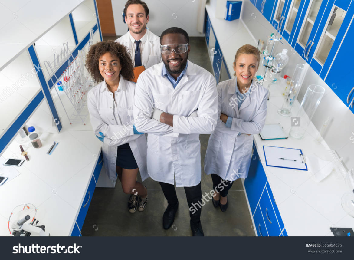 stock-photo-african-american-scientist-with-group-of-researchers-in-modern-laboratory-happy-smiling-mix-race-665954035.jpg