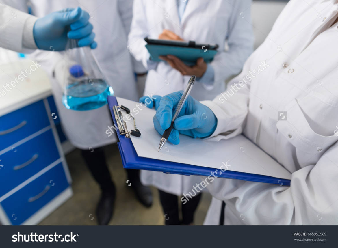 stock-photo-closeup-of-scientist-holding-flask-and-group-of-students-taking-notes-about-liquid-in-laboratory-665953969.jpg